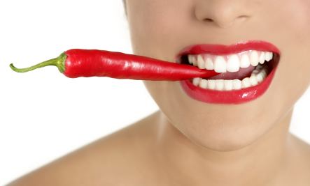 Beautiful woman teeth eating red pepper